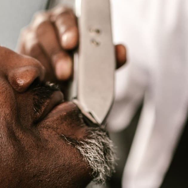 Barber shaping a gray goatee with a trimmer