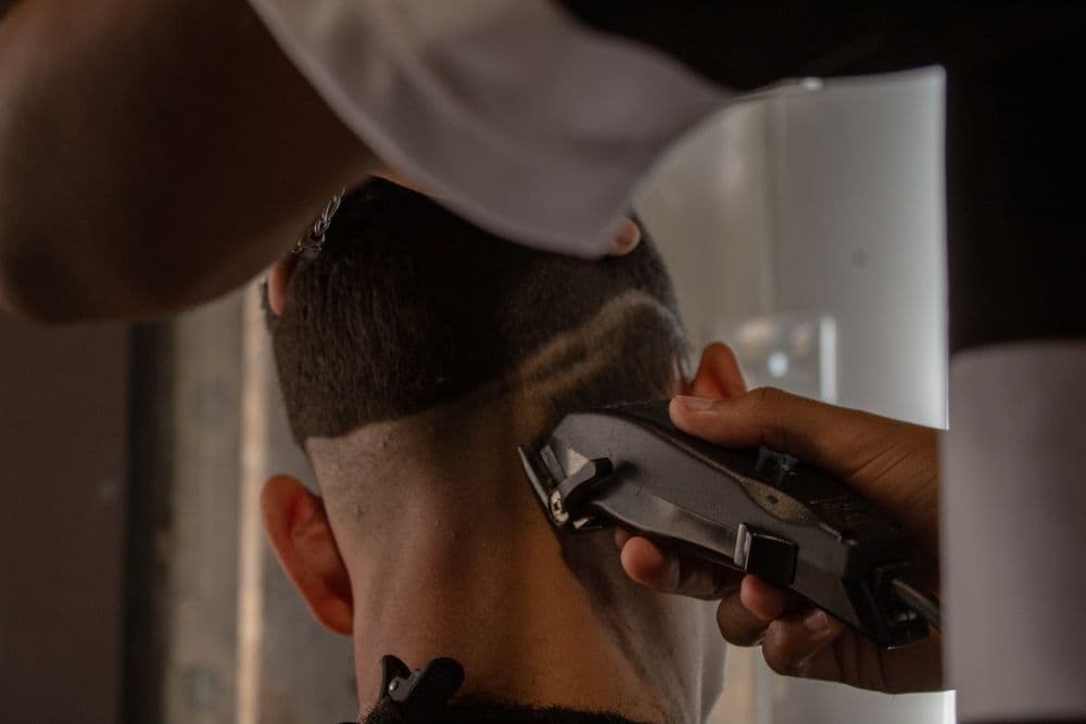 Barber carving a fade with a design line using clippers